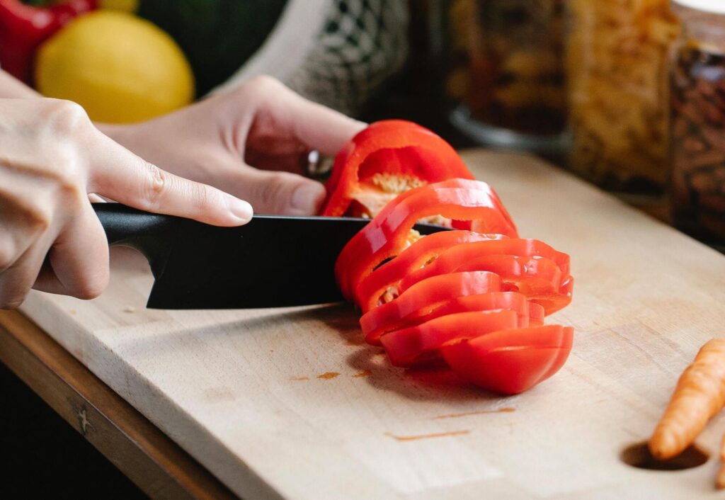 A cook chops a red pepper
